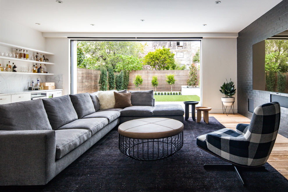 Immagine di un soggiorno design con angolo bar, pareti nere, pavimento in legno massello medio, TV a parete e pavimento marrone