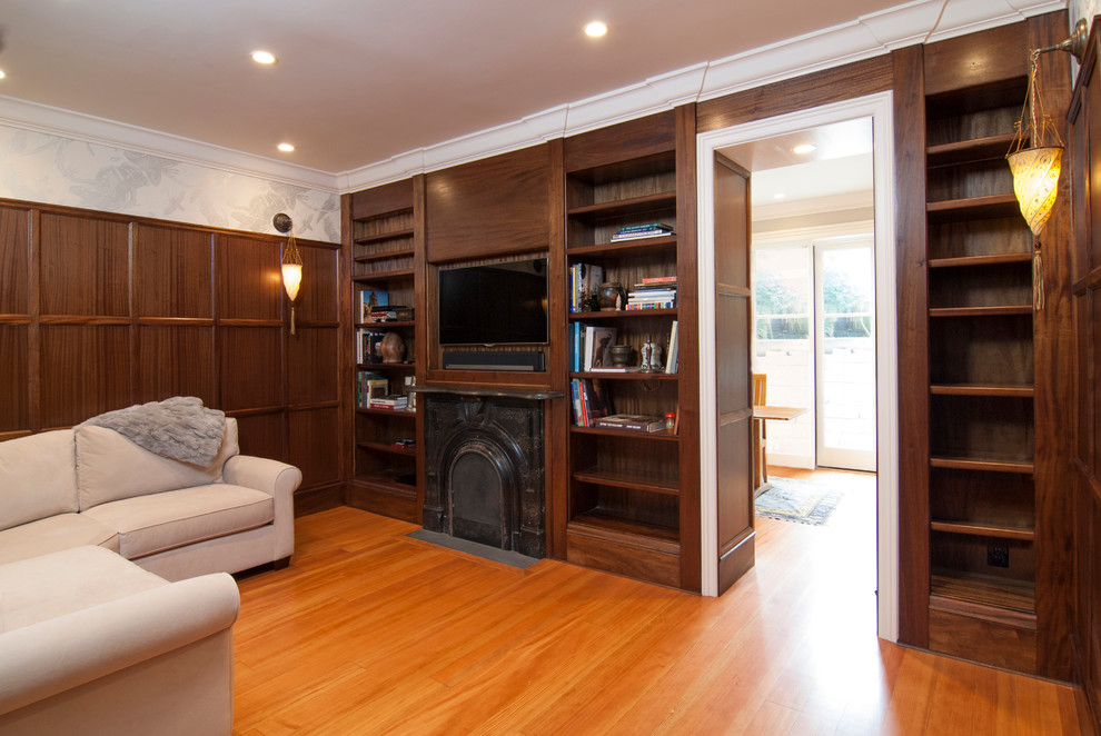 Kleine, Abgetrennte Klassische Bibliothek mit brauner Wandfarbe, hellem Holzboden, Kamin, Kaminumrandung aus Metall und TV-Wand in San Francisco