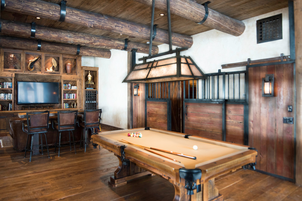 This is an example of an expansive rustic open plan games room in Albuquerque with a game room, beige walls, medium hardwood flooring and a built-in media unit.