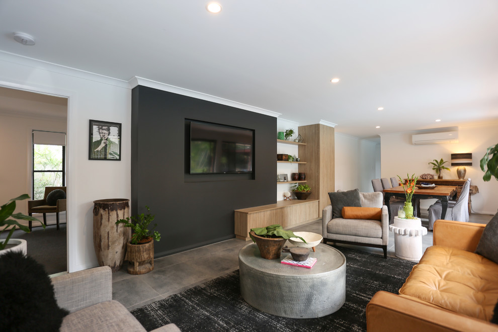На фото: открытая гостиная комната среднего размера в стиле фьюжн с черными стенами, полом из керамической плитки, телевизором на стене и серым полом