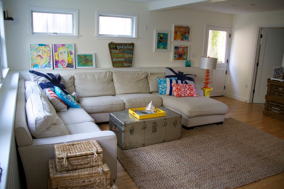 Imagen de sala de estar abierta costera de tamaño medio con paredes blancas, suelo de madera clara y televisor independiente