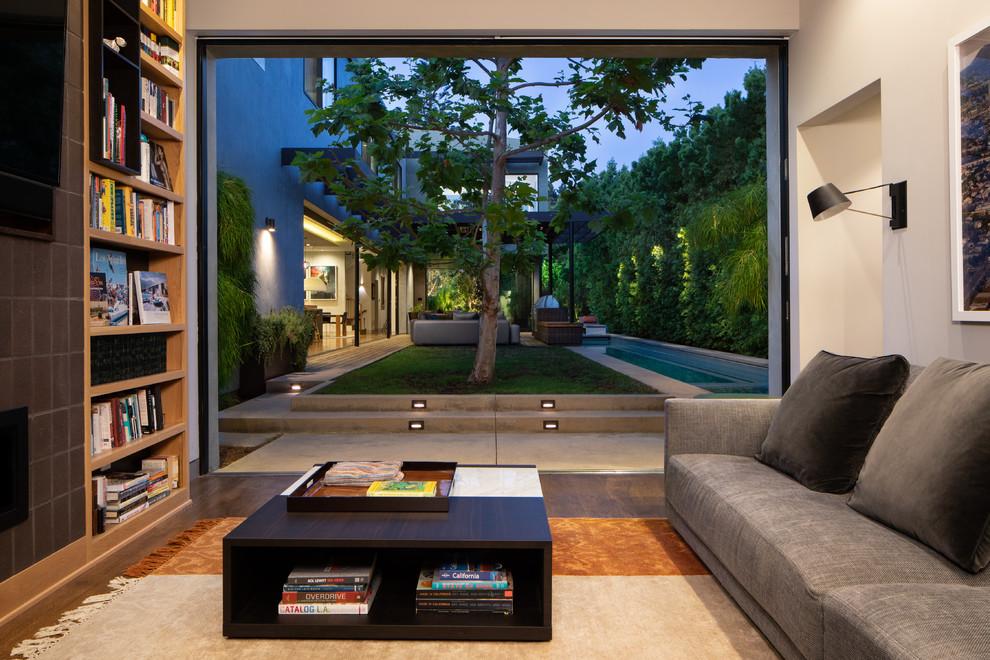 Offenes Modernes Wohnzimmer mit weißer Wandfarbe, dunklem Holzboden, TV-Wand und braunem Boden in Los Angeles