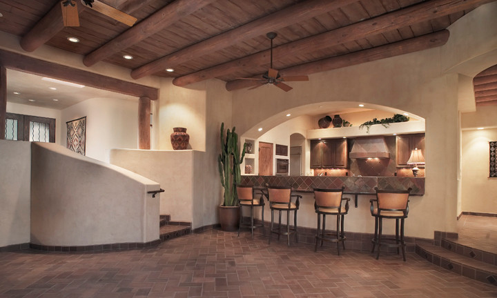 Mittelgroßes, Offenes Mediterranes Wohnzimmer mit beiger Wandfarbe, Terrakottaboden, Eckkamin, verputzter Kaminumrandung und verstecktem TV in Phoenix