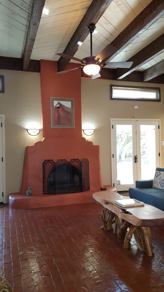 Example of a large southwest open concept brick floor family room design in Albuquerque with beige walls, a standard fireplace and a plaster fireplace