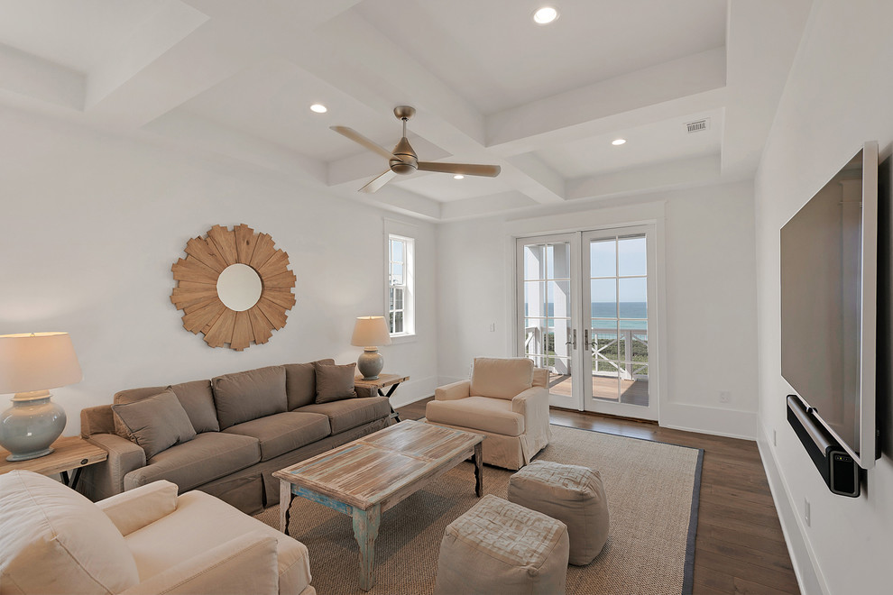 Foto de sala de estar cerrada costera de tamaño medio sin chimenea y televisor con paredes blancas, suelo de madera en tonos medios y suelo beige