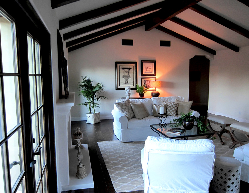 Cette image montre une salle de séjour méditerranéenne de taille moyenne et ouverte avec un mur blanc, parquet foncé, une cheminée standard, un manteau de cheminée en béton et un sol marron.
