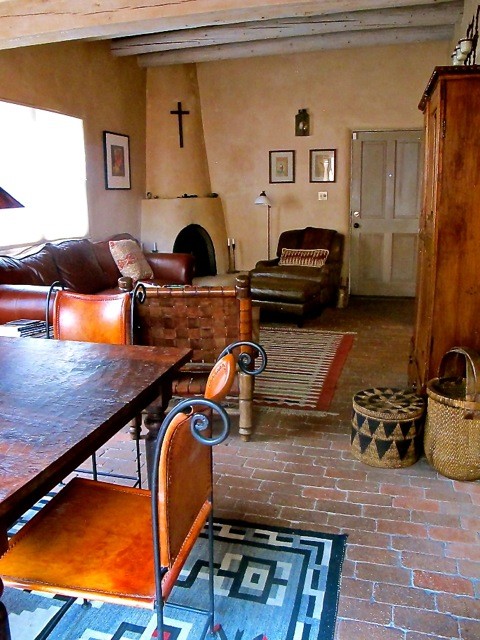 Esempio di un soggiorno stile rurale di medie dimensioni e aperto con pareti beige, pavimento in mattoni, camino ad angolo, cornice del camino in intonaco e nessuna TV
