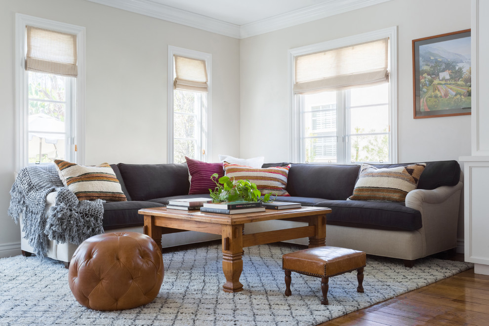 Example of a mid-sized transitional enclosed medium tone wood floor and brown floor family room design in Los Angeles with beige walls and no fireplace