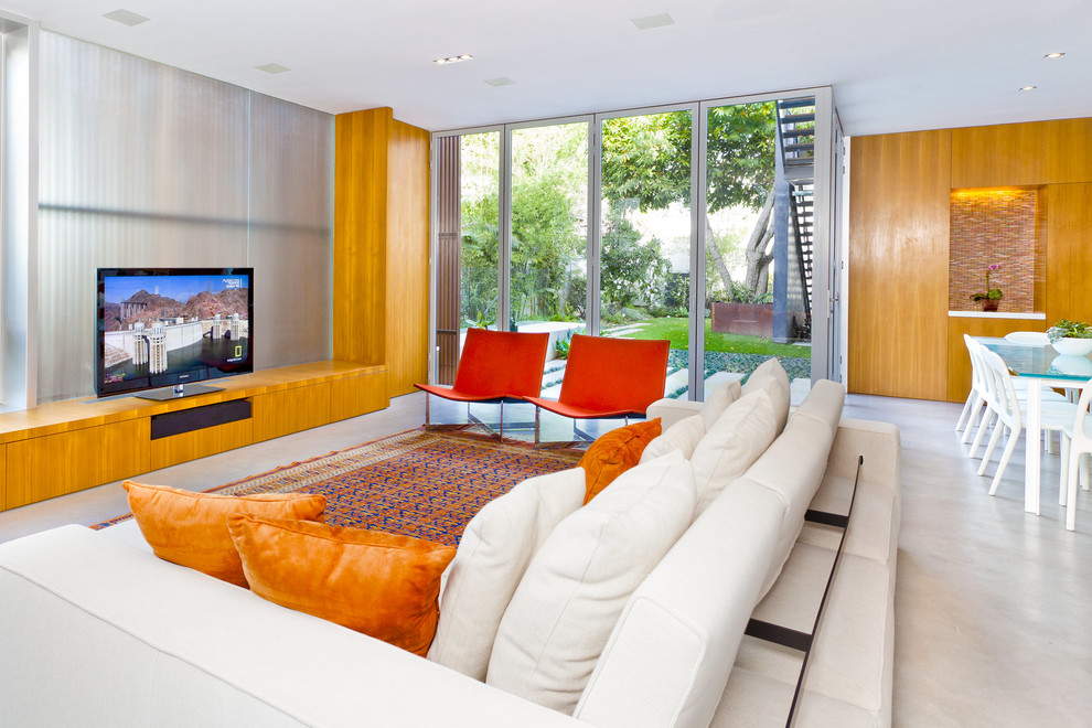 На фото: большая открытая гостиная комната в стиле модернизм с бетонным полом и отдельно стоящим телевизором с