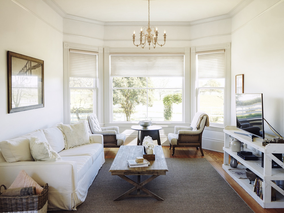 Imagen de sala de estar cerrada romántica de tamaño medio sin chimenea con paredes blancas, suelo de madera en tonos medios, televisor independiente y suelo marrón