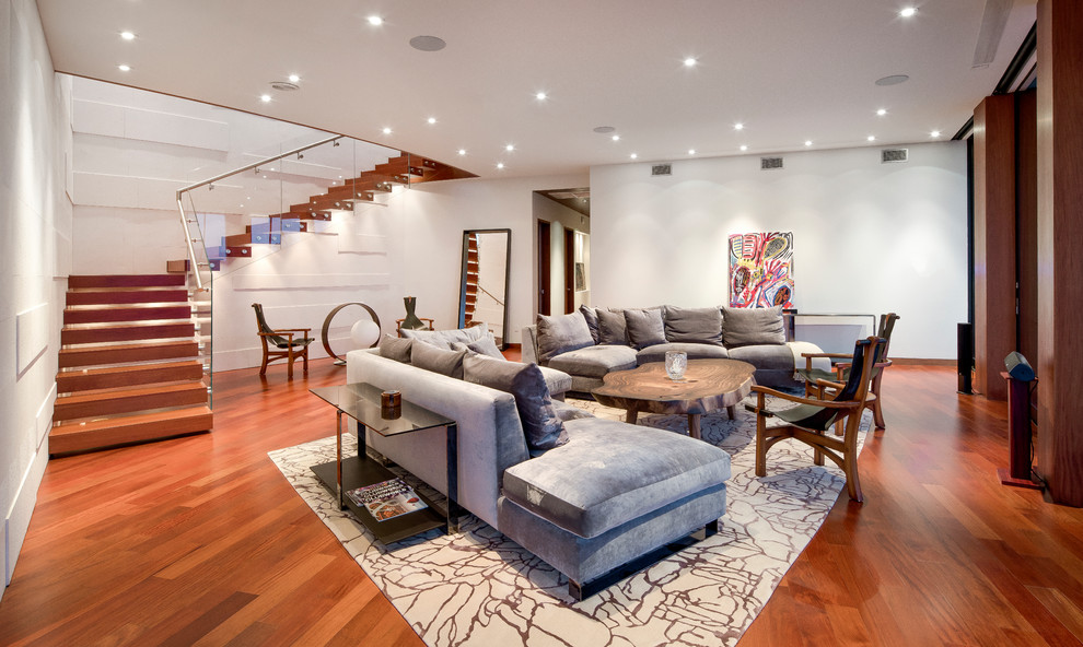 Imagen de sala de estar abierta actual grande sin chimenea y televisor con paredes blancas, suelo de madera en tonos medios y suelo rojo
