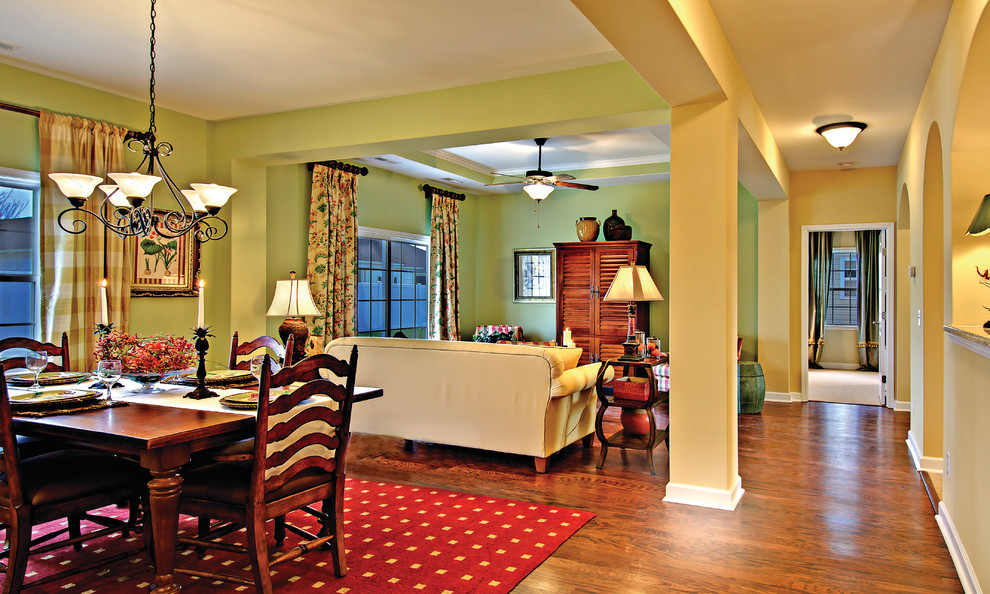 На фото: открытая гостиная комната среднего размера в классическом стиле с зелеными стенами, темным паркетным полом и скрытым телевизором без камина