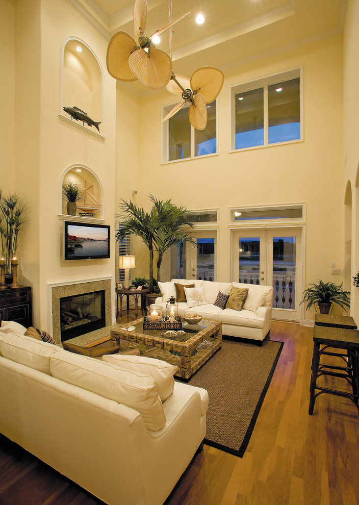 Пример оригинального дизайна: большая открытая гостиная комната в морском стиле с желтыми стенами, паркетным полом среднего тона, стандартным камином, фасадом камина из камня и телевизором на стене