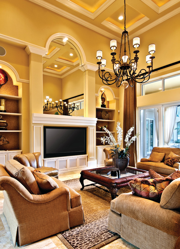 Diseño de sala de estar abierta mediterránea grande sin chimenea con paredes amarillas, suelo de travertino y pared multimedia