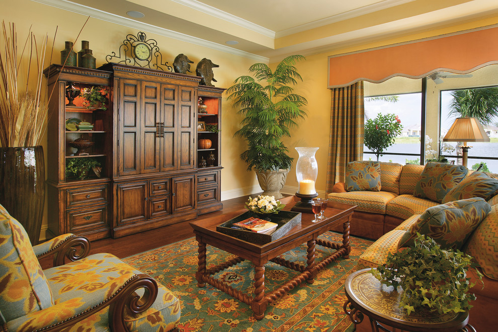 Imagen de sala de estar abierta de estilo de casa de campo grande sin chimenea con paredes amarillas, suelo de madera oscura y televisor retractable