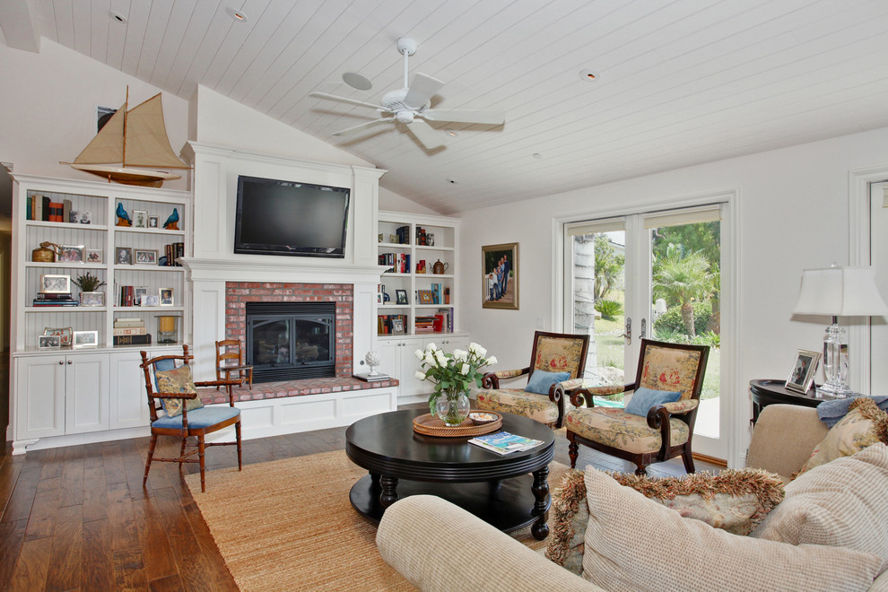Elegant medium tone wood floor family room photo in San Diego with white walls, a standard fireplace, a brick fireplace and a wall-mounted tv