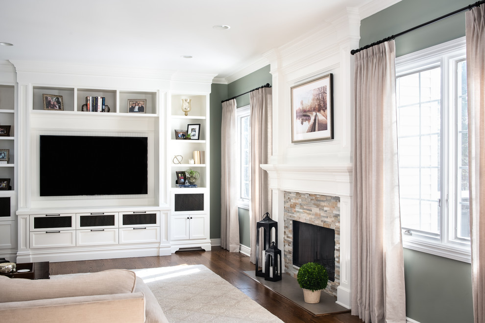Cette image montre une salle de séjour traditionnelle de taille moyenne et fermée avec un mur vert, un sol en bois brun, une cheminée standard, un manteau de cheminée en pierre, un téléviseur encastré et un sol marron.