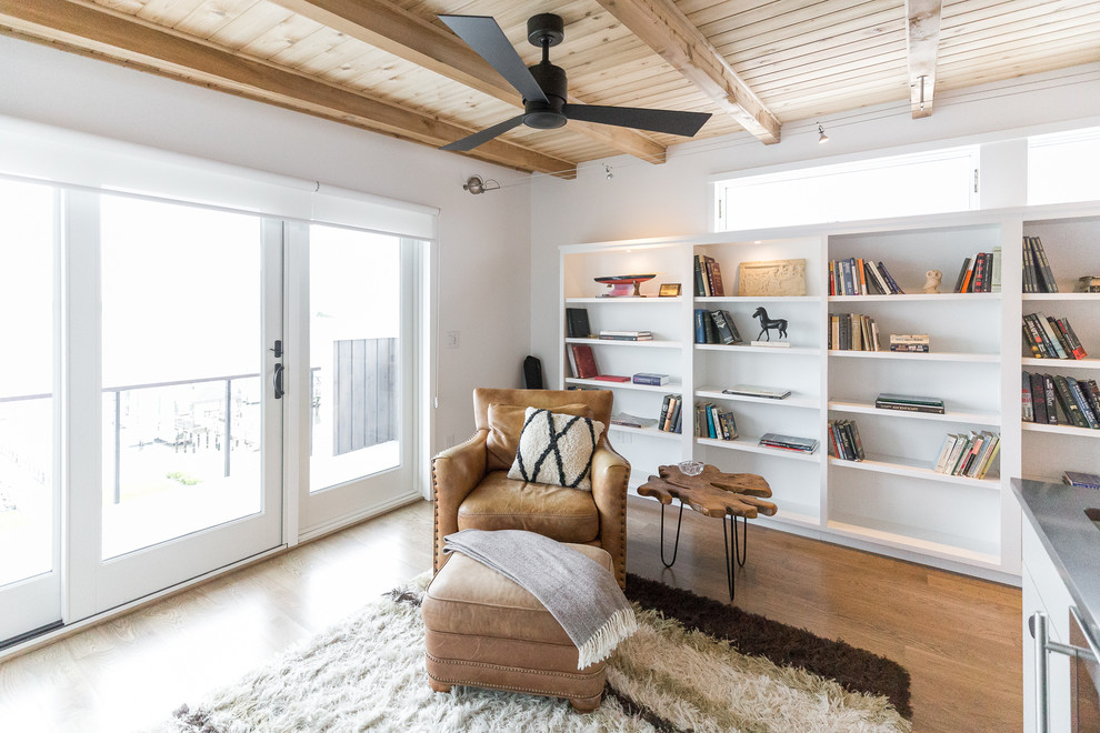 Esempio di un soggiorno moderno di medie dimensioni e aperto con libreria, pareti bianche, pavimento in legno massello medio, TV a parete e pavimento grigio