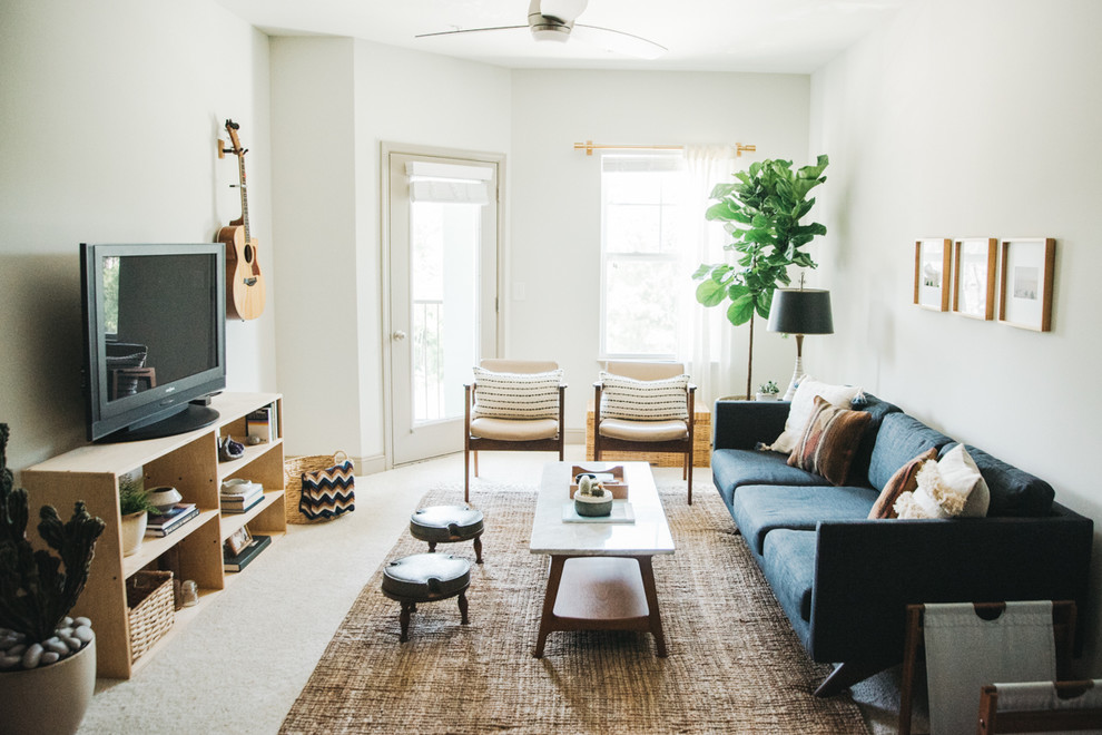 Идея дизайна: гостиная комната в скандинавском стиле с белыми стенами, ковровым покрытием, отдельно стоящим телевизором, бежевым полом и синим диваном