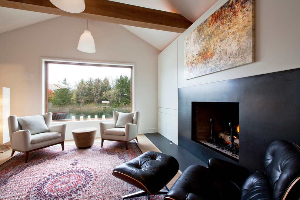 Exemple d'une salle de séjour tendance de taille moyenne et ouverte avec un mur blanc, un sol en bois brun, une cheminée standard, un manteau de cheminée en métal et un téléviseur dissimulé.