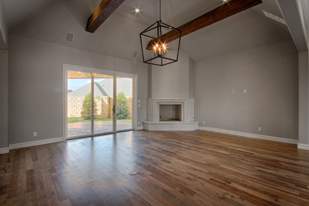 Imagen de sala de estar abierta minimalista con paredes grises, suelo de madera en tonos medios, chimenea de esquina y televisor colgado en la pared