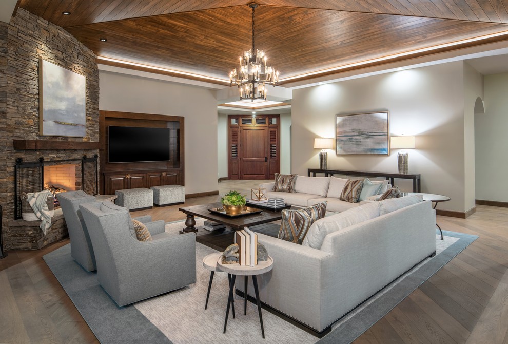 Diseño de sala de estar abierta contemporánea grande con paredes blancas, suelo de madera en tonos medios, chimenea de esquina, marco de chimenea de piedra y suelo marrón