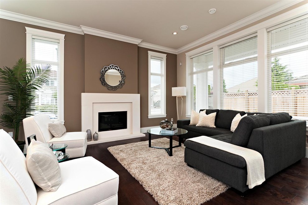 Diseño de sala de estar actual sin televisor con paredes marrones, suelo de madera oscura y todas las chimeneas