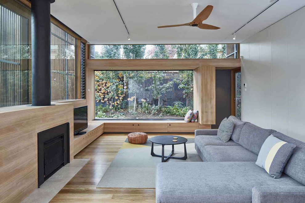 Exempel på ett modernt allrum, med mellanmörkt trägolv, en öppen vedspis, en fristående TV och brunt golv