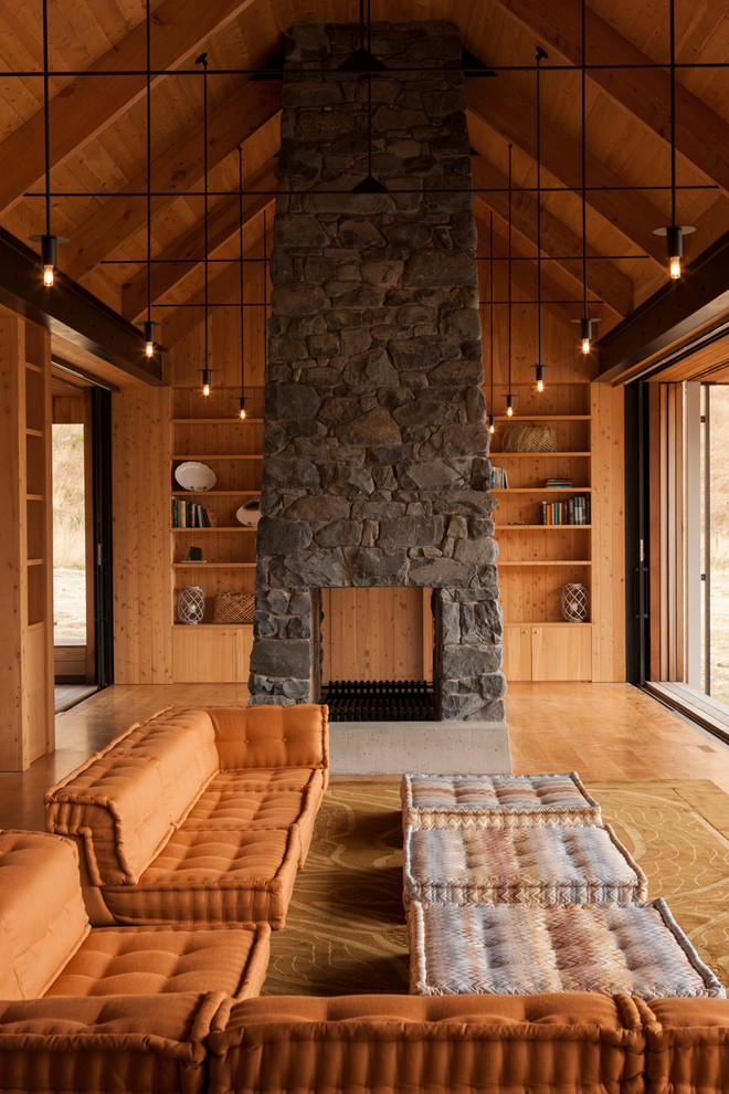 Uriges Wohnzimmer mit brauner Wandfarbe, braunem Holzboden, Tunnelkamin, Kaminumrandung aus Stein und braunem Boden