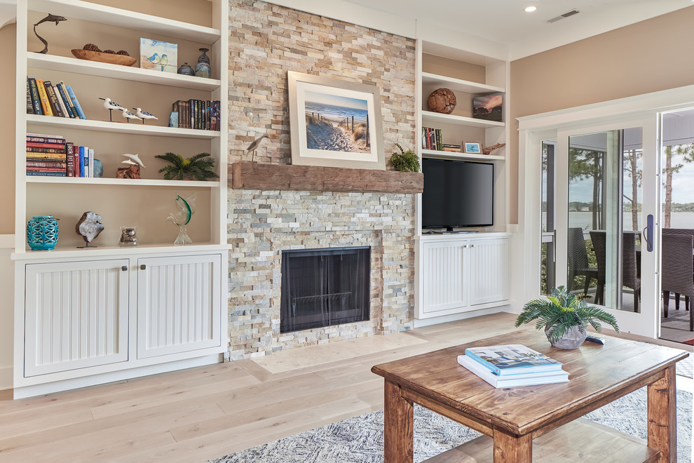 Example of a large beach style open concept light wood floor and beige floor family room library design in Charleston with beige walls, a standard fireplace, a stone fireplace and a tv stand