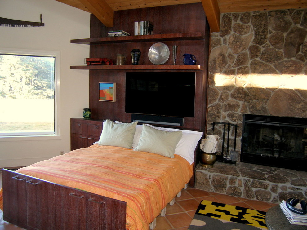 Cette image montre une salle de séjour design de taille moyenne et ouverte avec tomettes au sol, une cheminée standard, un manteau de cheminée en pierre et un téléviseur fixé au mur.