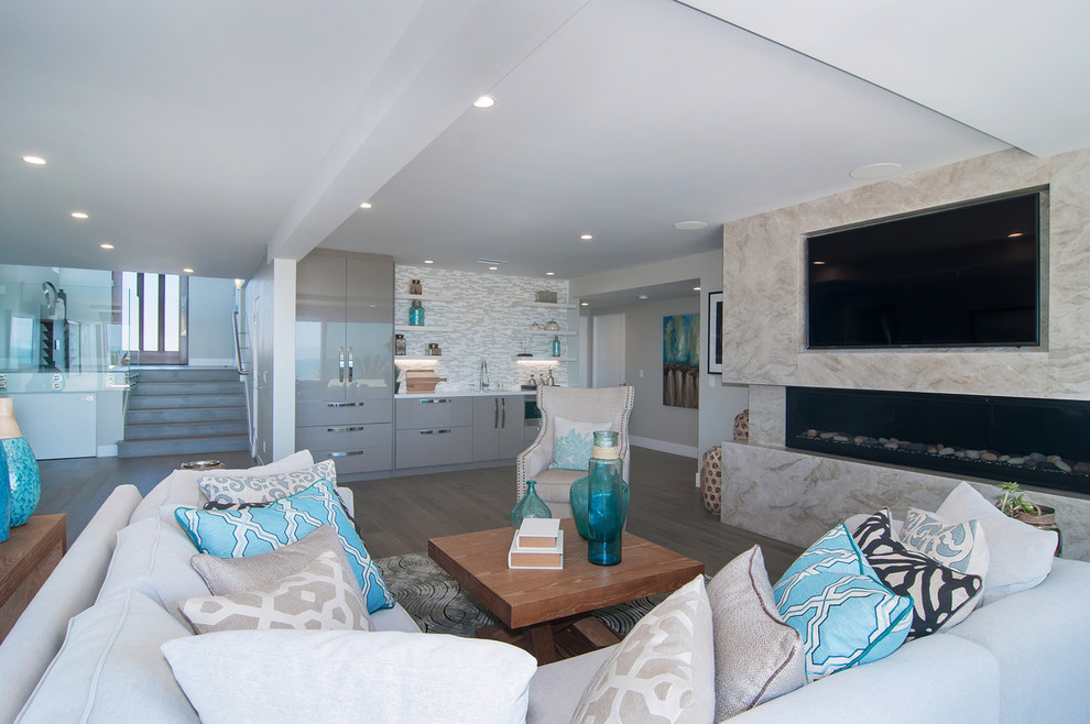 Mittelgroßes, Offenes Maritimes Wohnzimmer mit grauer Wandfarbe, hellem Holzboden, Gaskamin, Kaminumrandung aus Stein und TV-Wand in San Diego