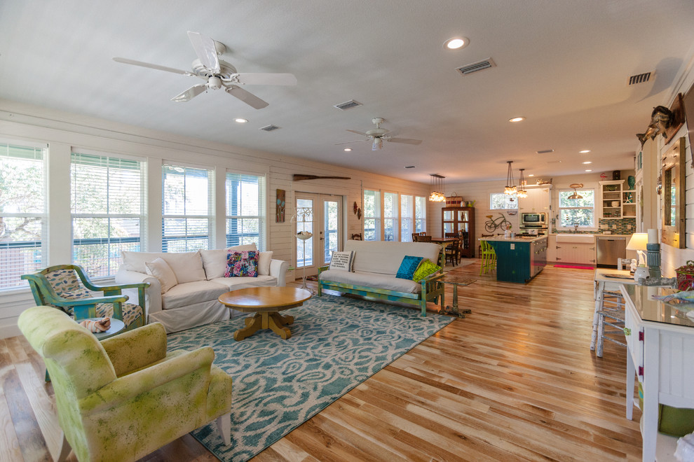 Diseño de sala de estar costera grande con paredes blancas, suelo de madera clara y suelo beige