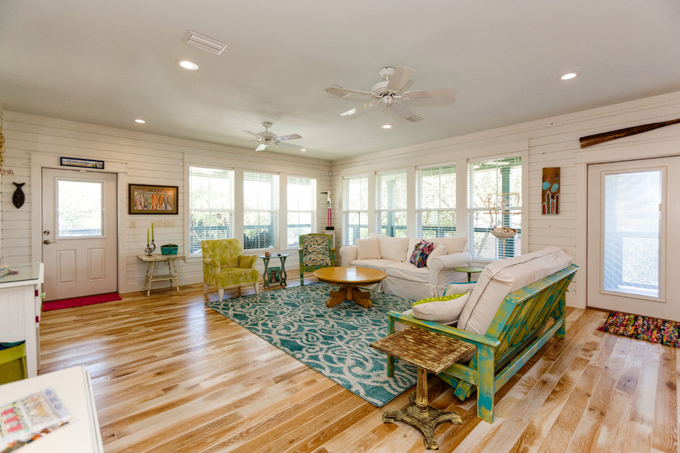 Imagen de sala de estar costera grande con paredes blancas, suelo de madera clara y suelo beige