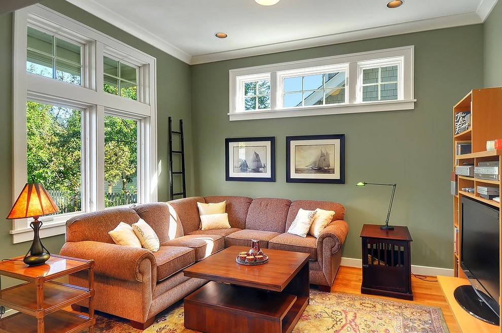 Réalisation d'une salle de séjour craftsman avec un mur vert, un sol en bois brun et un téléviseur indépendant.