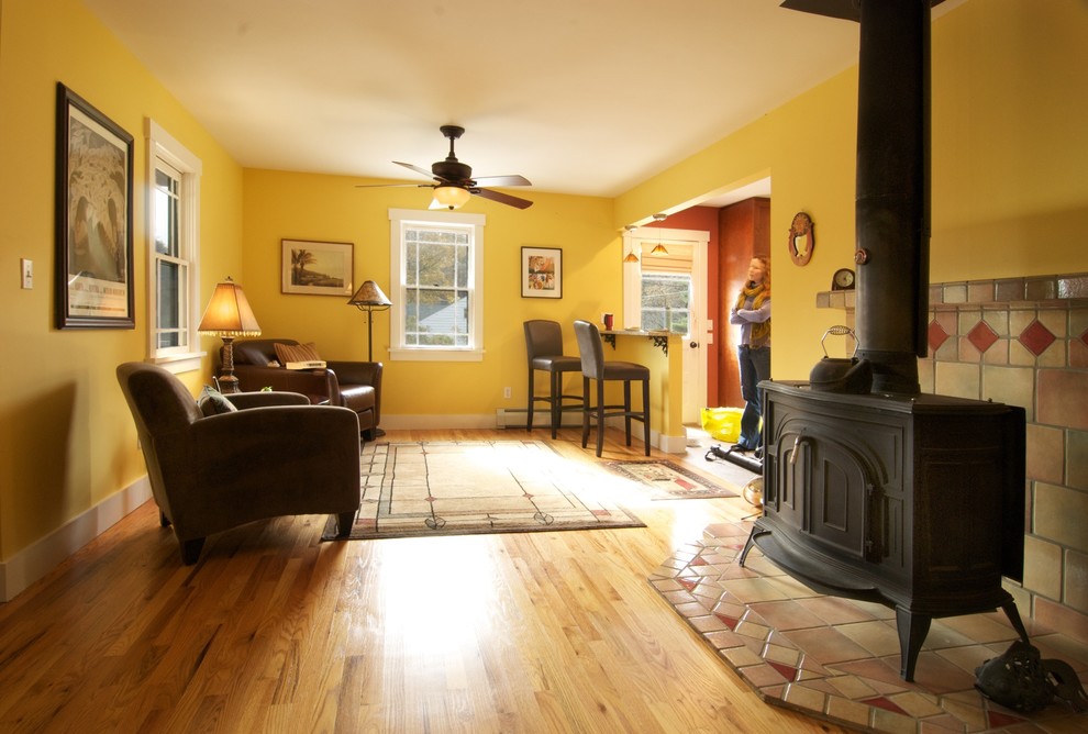 Cette photo montre une salle de séjour craftsman de taille moyenne et ouverte avec un mur jaune, un sol en bois brun et un poêle à bois.