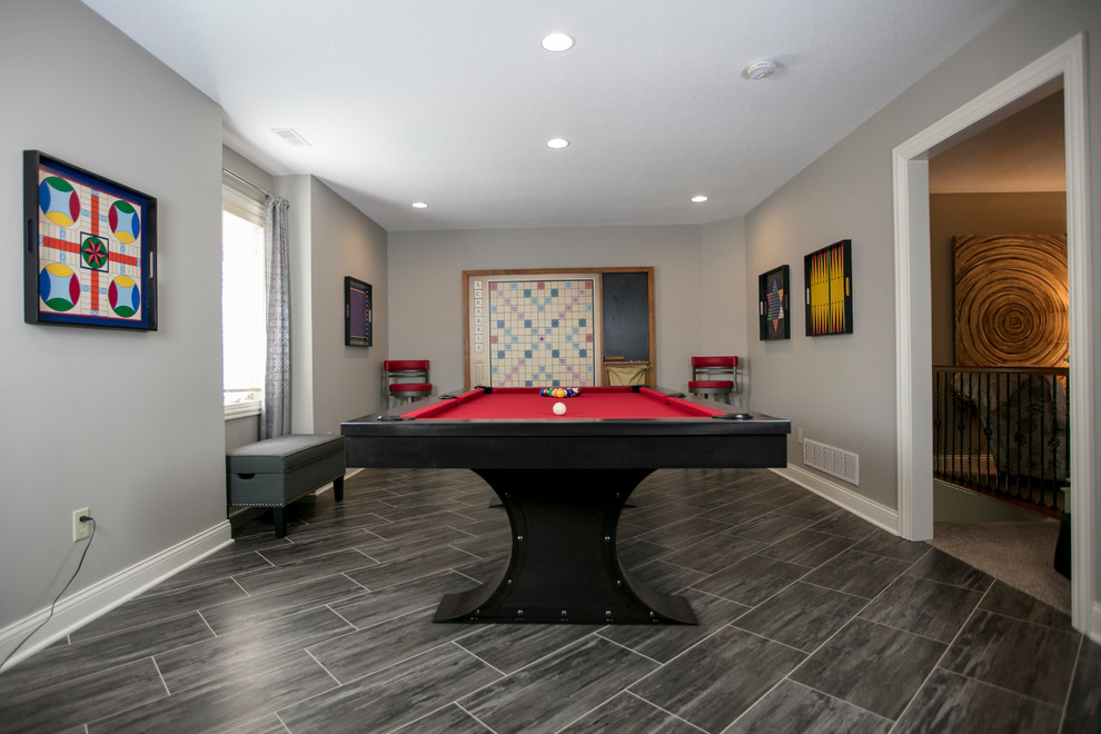 Modelo de sala de juegos en casa abierta tradicional grande con paredes grises, suelo vinílico, televisor independiente y suelo gris