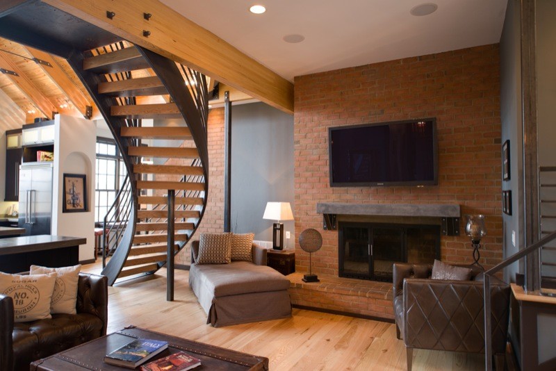 Ejemplo de sala de estar abierta contemporánea grande con suelo de madera clara, todas las chimeneas, marco de chimenea de ladrillo y televisor colgado en la pared