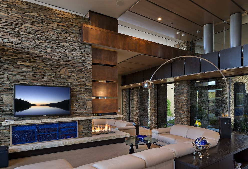 Inspiration for a large contemporary open concept concrete floor and beige floor family room remodel in Phoenix with beige walls, a wall-mounted tv, a corner fireplace and a stone fireplace