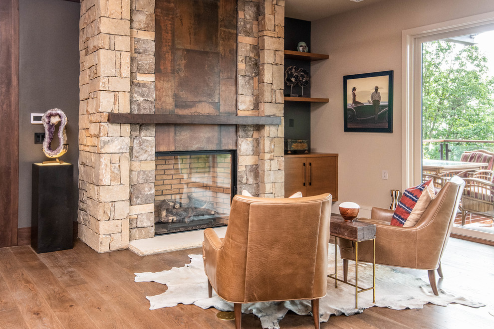 Cette image montre une grande salle de séjour vintage ouverte avec un mur beige, parquet foncé, une cheminée standard, un manteau de cheminée en pierre et un sol marron.