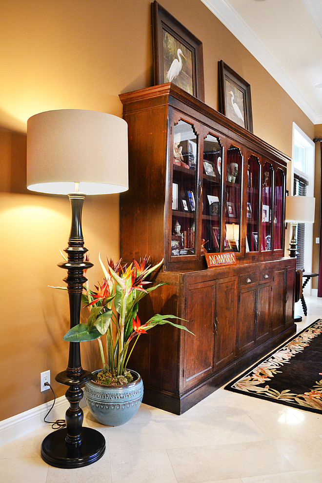 Imagen de sala de estar cerrada tropical grande con paredes beige, suelo de baldosas de cerámica y televisor independiente
