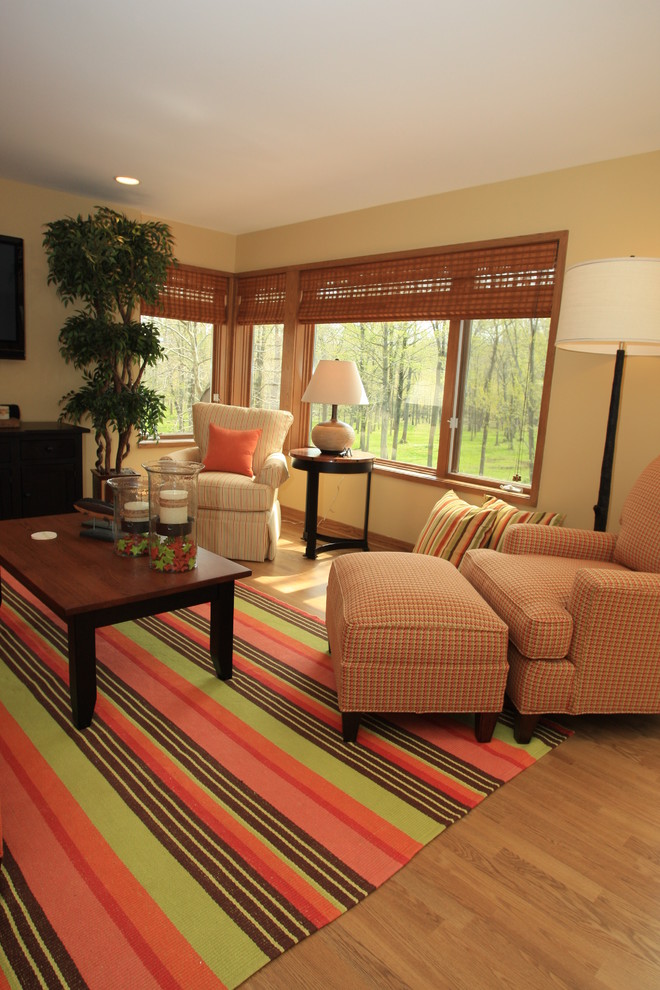 Идея дизайна: открытая гостиная комната среднего размера в стиле фьюжн с желтыми стенами, паркетным полом среднего тона и телевизором на стене без камина