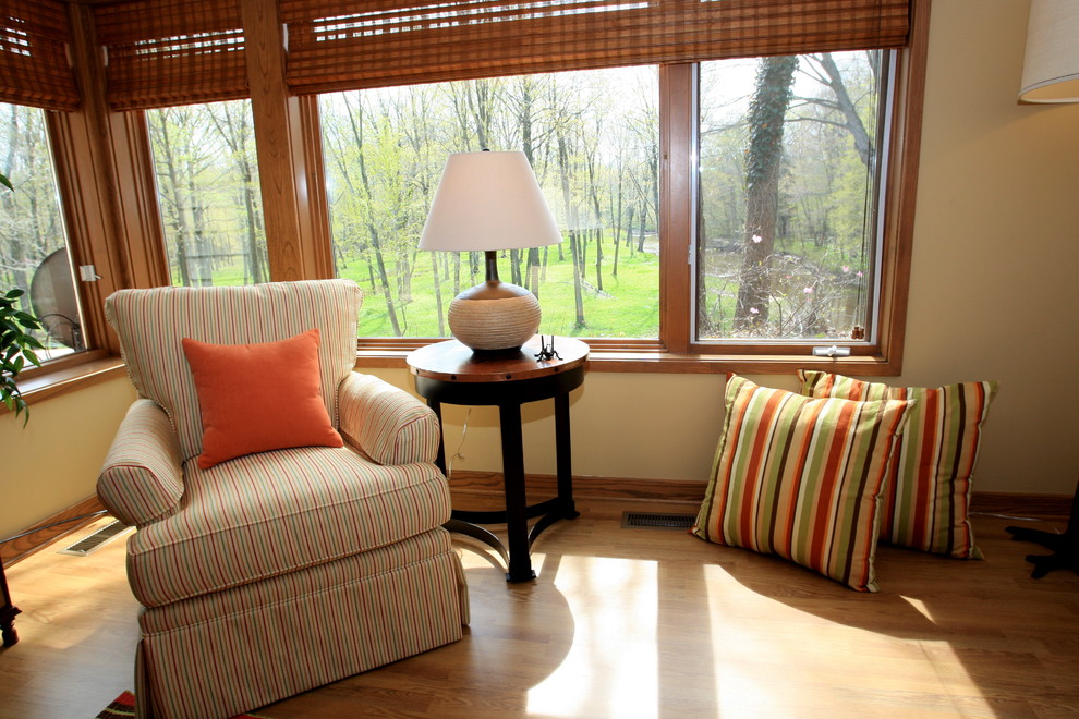 Foto de sala de estar abierta bohemia grande sin chimenea con paredes amarillas, suelo de madera en tonos medios y televisor colgado en la pared