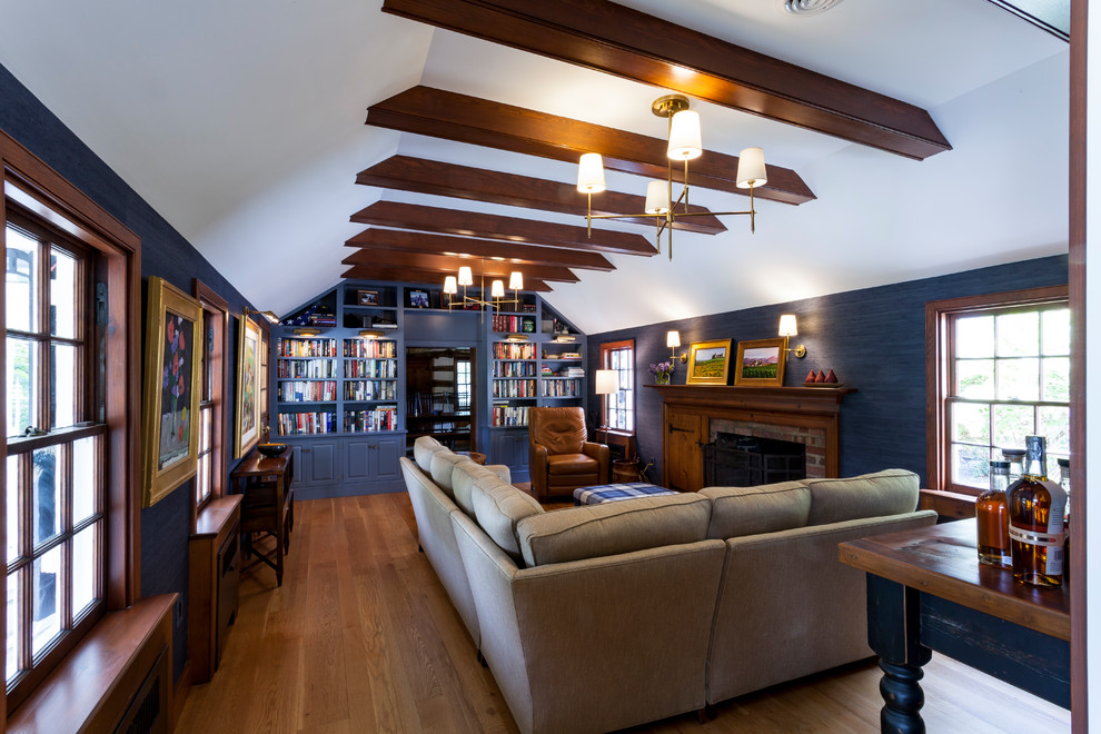 Diseño de sala de estar con biblioteca cerrada de estilo de casa de campo con paredes azules, suelo de madera clara, todas las chimeneas y marco de chimenea de ladrillo