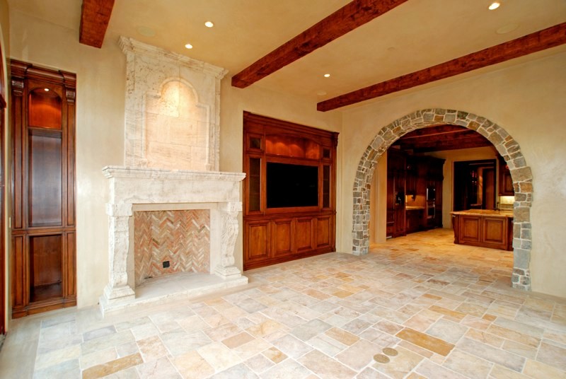 Exempel på ett mellanstort rustikt avskilt allrum, med beige väggar, kalkstensgolv, en standard öppen spis, en spiselkrans i sten och en inbyggd mediavägg