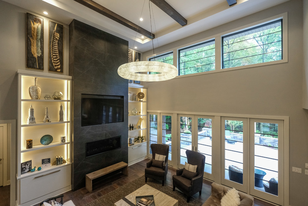 Modelo de sala de estar abierta contemporánea grande con paredes grises, suelo de madera oscura, todas las chimeneas, marco de chimenea de baldosas y/o azulejos y televisor colgado en la pared