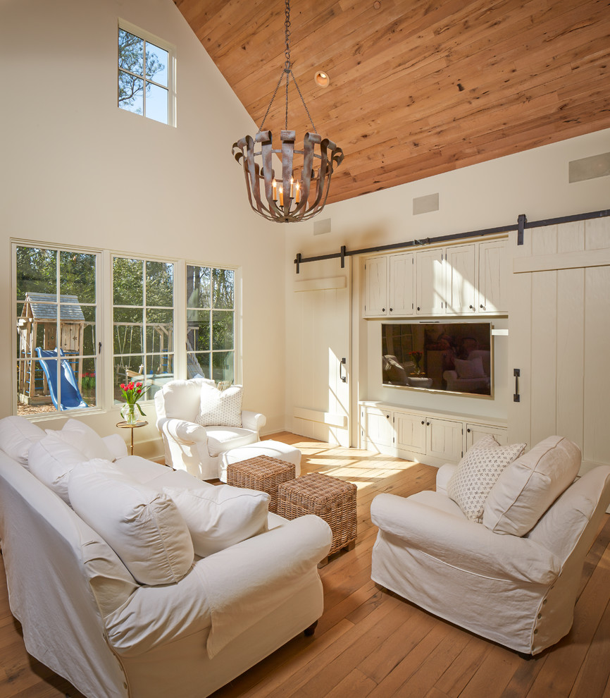 Mid-sized elegant enclosed medium tone wood floor and brown floor family room photo in Houston with a media wall, white walls and no fireplace