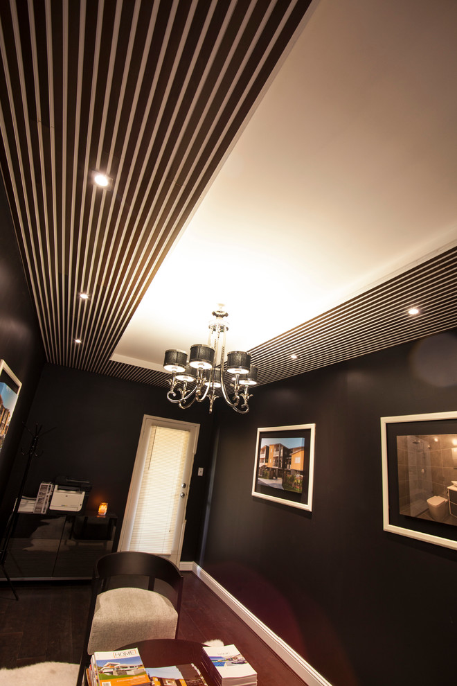 На фото: изолированная гостиная комната среднего размера в стиле модернизм с с книжными шкафами и полками, деревянным полом, телевизором на стене и черными стенами с