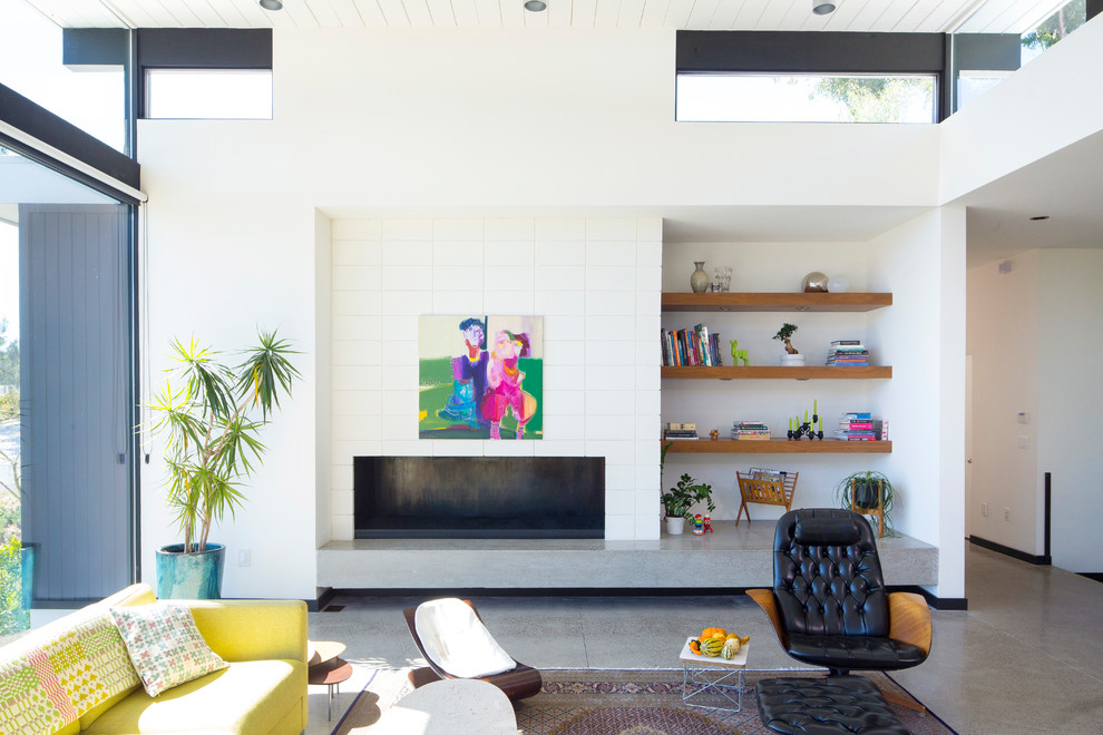 Diseño de sala de estar abierta retro con paredes blancas, suelo de cemento, chimenea lineal, suelo gris y alfombra