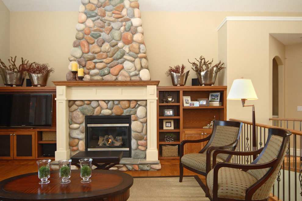 Diseño de sala de estar abierta clásica renovada de tamaño medio con paredes beige, suelo de madera en tonos medios, todas las chimeneas, marco de chimenea de piedra y televisor independiente